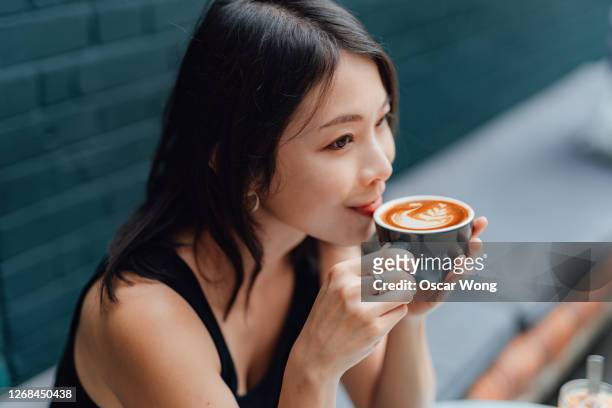 young woman enjoying a peaceful morning with a cup of coffee in cafe - asian coffee at cafe imagens e fotografias de stock