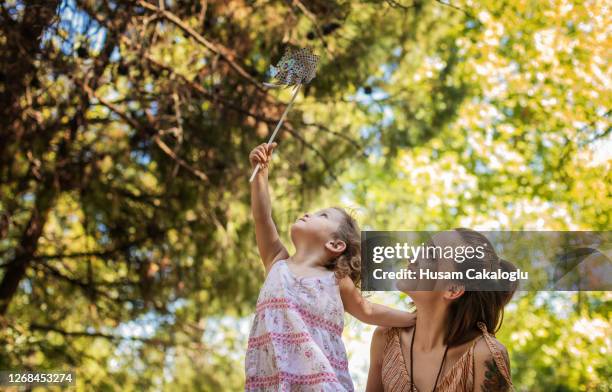 mutter und ihre niedliche kleine tochter spielen mit zahnrad-spielzeug im park. - mother and daughter in the wind stock-fotos und bilder