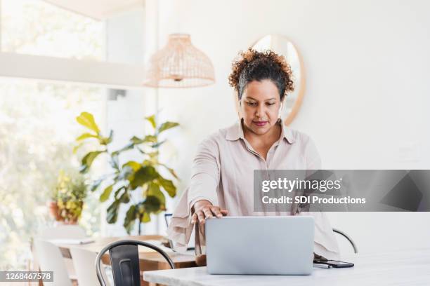 woman standing at kitchen counter shuts down laptop - closed laptop stock pictures, royalty-free photos & images