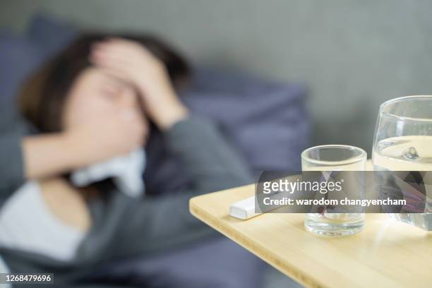 sick woman lying on bed blowing nose. - tissue box stockfoto's en -beelden