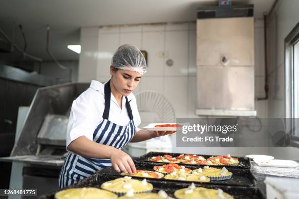 baker woman preparing mini pizzas at commercial kitchen - hair net stock pictures, royalty-free photos & images