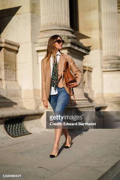 Natalia Verza wears sunglasses from Celine, a Paul & Joe beige blazer jacket, a white shirt, a colored floral print tie from Paul & Joe, blue denim...