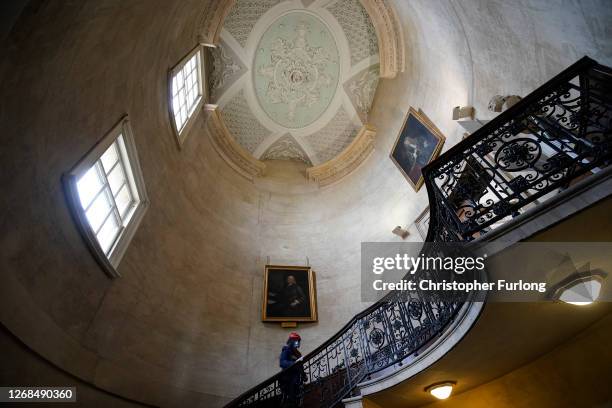 Front of House Visitor Host Jessica Baudet poses as she sanitises touch areas on the staircase of the Radcliffe Camera at the Bodleian Library on...