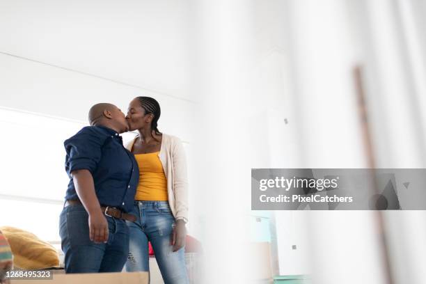 african lesbian couple kiss standing in new home - black lesbians kiss stock pictures, royalty-free photos & images