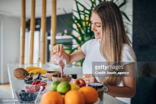 hermosa mujer preparando un desayuno saludable - smoothie bowl fotografías e imágenes de stock