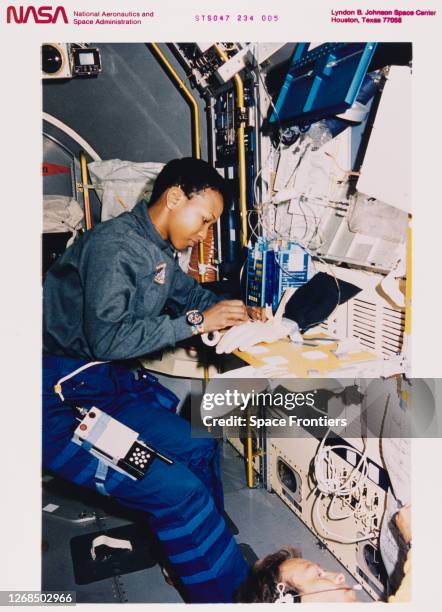American NASA astronaut Mae Jemison conducts a Fluid Therapy System experiment procedure, injecting a fluid into a mannequin's hand during research...