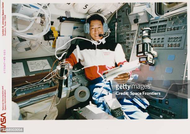 Japanese NASDA astronaut Mamoru Mohri, wearing a headset to communicate with students from the aft flight deck of the Earth-orbiting Space Shuttle...