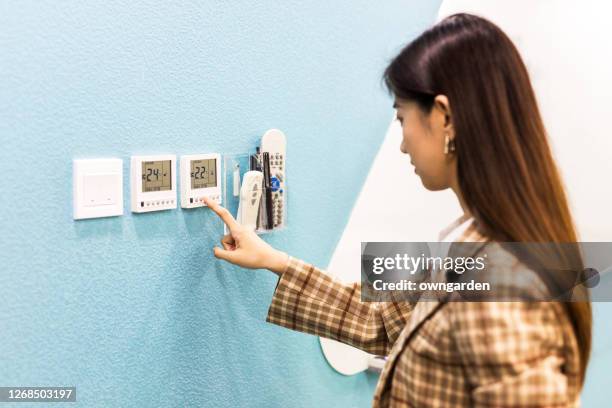 business women push button digital thermostat - air conditioner interior wall stock pictures, royalty-free photos & images