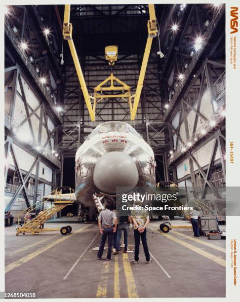 Space Shuttle Discovery about to be hoisted into a tail-toward-ground mode for mating to its two solid rocket boosters and an external tank in the...