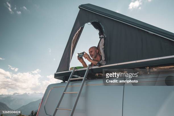 man camping with tent on car roof - car roof stock pictures, royalty-free photos & images