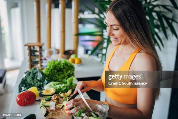 eine fitte frau, die gesunden gemüsesalat zum frühstück macht - sportkleidung stock-fotos und bilder