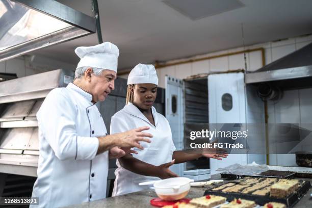 senior chef explaining something to an assistant - chef teaching stock pictures, royalty-free photos & images
