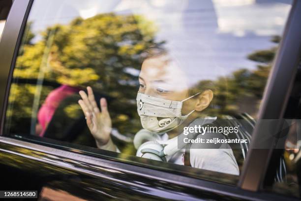 girl with protective mask peeking through the car window - kid peeking stock pictures, royalty-free photos & images