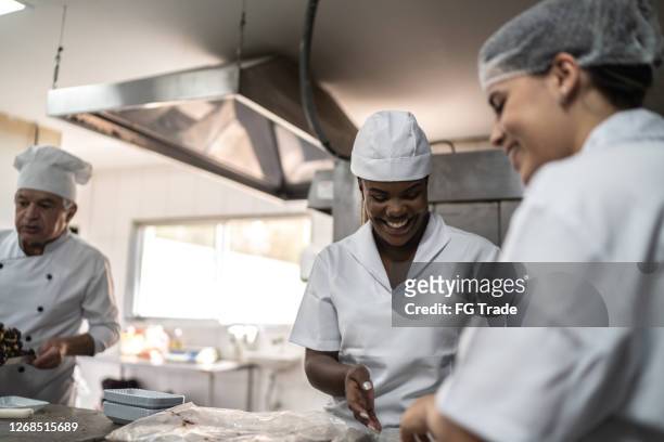 due chef preparano brigadeiros in una cucina commerciale - cafeteria foto e immagini stock