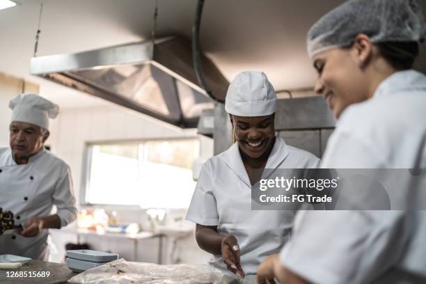 two chefs preparing brigadeiros in a commercial kitchen - chef patissier stock pictures, royalty-free photos & images