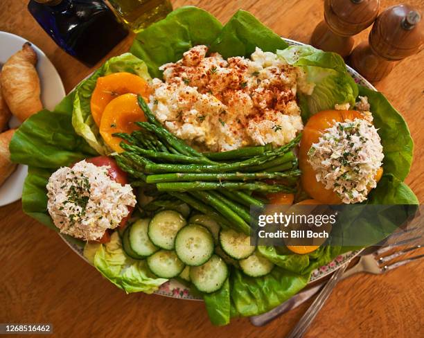 summer serving platter loaded with stuffed tomatoes, potato salad, fruits and vegetables on a wood table with olive oil, balsamic vinegar and salt and pepper grinders - peche au thon photos et images de collection