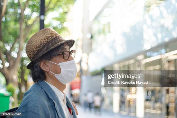 een man met een masker gaat door de straten van tokio. - omotesando tokio stockfoto's en -beelden