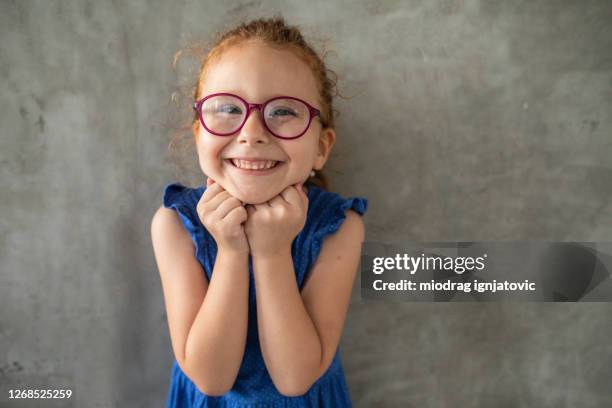 redhead cross-eyed girl standing in front of gray wall at home - cute five year old stock pictures, royalty-free photos & images
