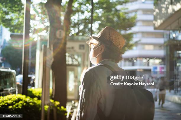 ein mann mit einer maske geht durch die straßen von tokio. - omotesando tokio stock-fotos und bilder