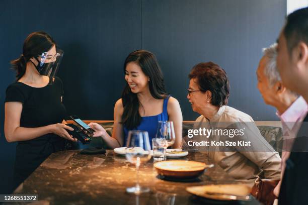 aziatische vrouw die mobiele betaling gebruikt om de rekening te regelen - singapore shopping family stockfoto's en -beelden