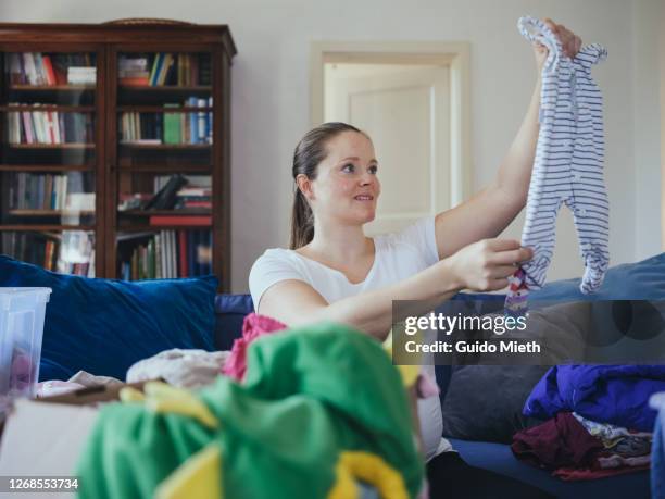 woman sorting used child clothes to avoid wasting. - possession stock pictures, royalty-free photos & images