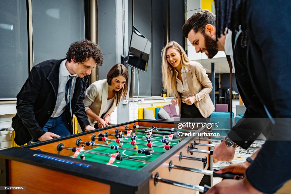 Businesspeople playing foosball in office