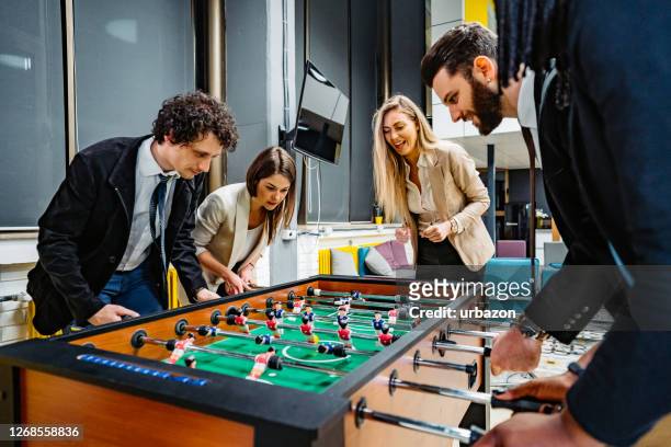 businesspeople playing foosball in office - incentive stock pictures, royalty-free photos & images