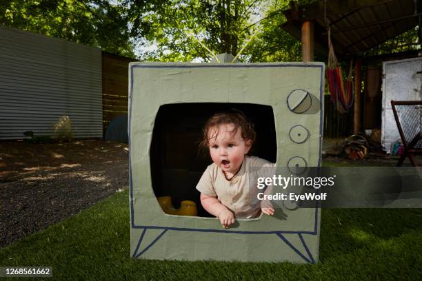 a babyclimbing out of a cardboard tv - insight tv stockfoto's en -beelden