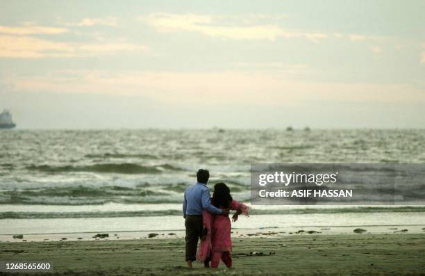 Pakistani young couple walk on a beach on Valentine's Day in Karachi, 14 February 2007. A number of shopping centers in Pakistan are full of gifts...