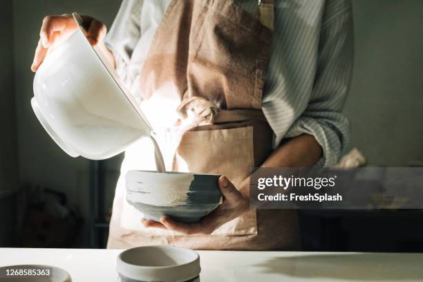 a woman artisan coloring ceramic bowl - glazen pot stock pictures, royalty-free photos & images