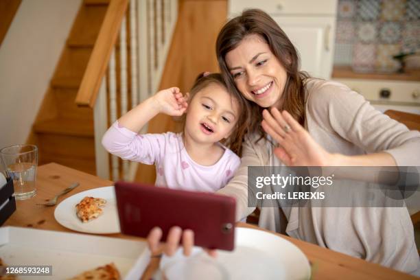 a young mother and a sweet daughter greet their family - mother daughter webcam stockfoto's en -beelden