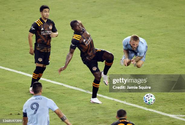 Johnny Russell of Sporting Kansas City is upended by Maynor Figueroa of Houston Dynamo during the game at Children's Mercy Park on August 25, 2020 in...