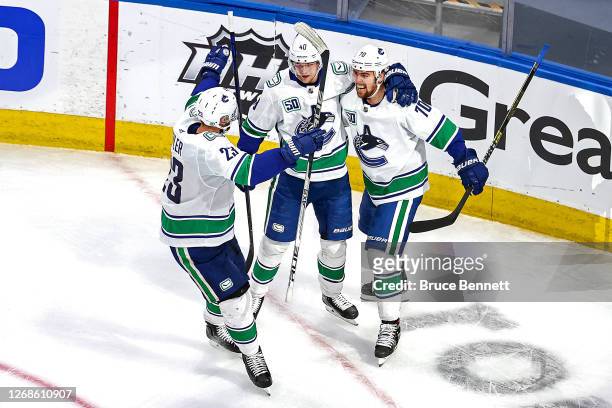 Elias Pettersson of the Vancouver Canucks is congratulated by his teammates, Alexander Edler and Tanner Pearson, after scoring a goal against the...
