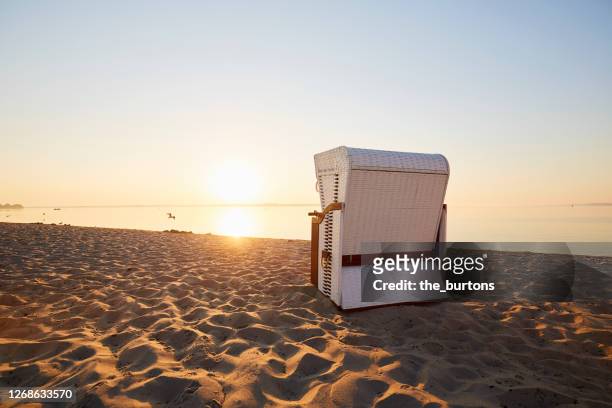 wicker beach chair at beach during sunset - strandkorb stock-fotos und bilder