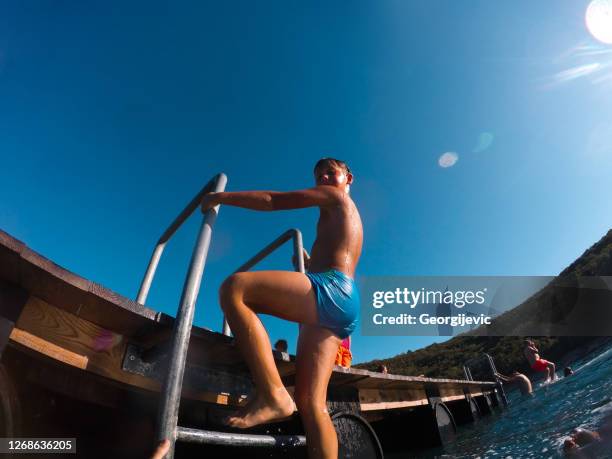 jungen spielen auf einer pierleiter - boy in swimwear stock-fotos und bilder