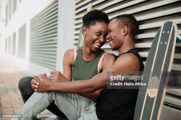 skater couple sitting on the sidewalk laughing - freedom united foundation stock-fotos und bilder