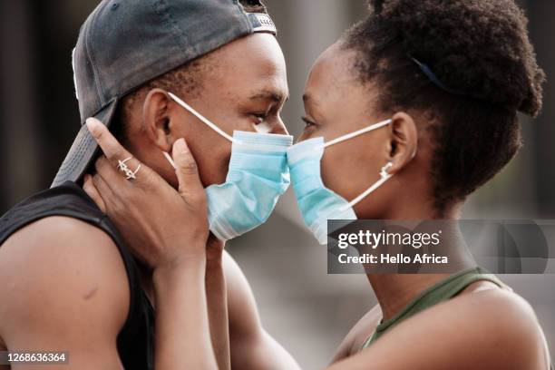 beautiful young couple wearing surgical face masks at close range - coronavirus dating stock pictures, royalty-free photos & images