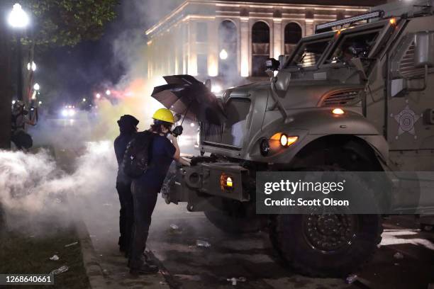 As tear gas fills the air, demonstrators confront police in front of the Kenosha County Courthouse during a third night of unrest on August 25, 2020...