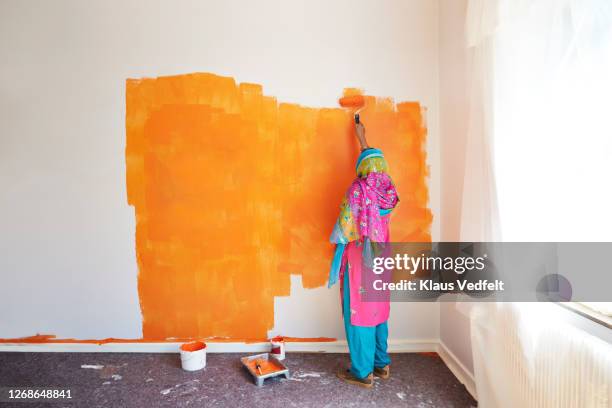 woman painting wall while renovating home - traditional clothing stock pictures, royalty-free photos & images