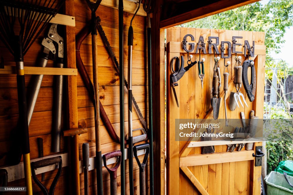 Interior de cobertizo de jardinería de madera con herramientas cuidadosamente dispuestas