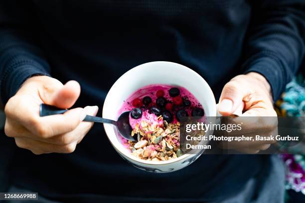 a man holding an acai, granola bowl - acai berries stockfoto's en -beelden