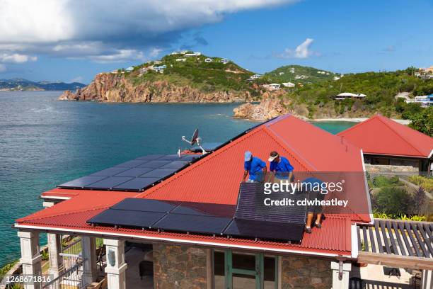 カリブ海の別荘の屋根にソーラーパネルを設置する労働者 - antilles ストックフォトと画像