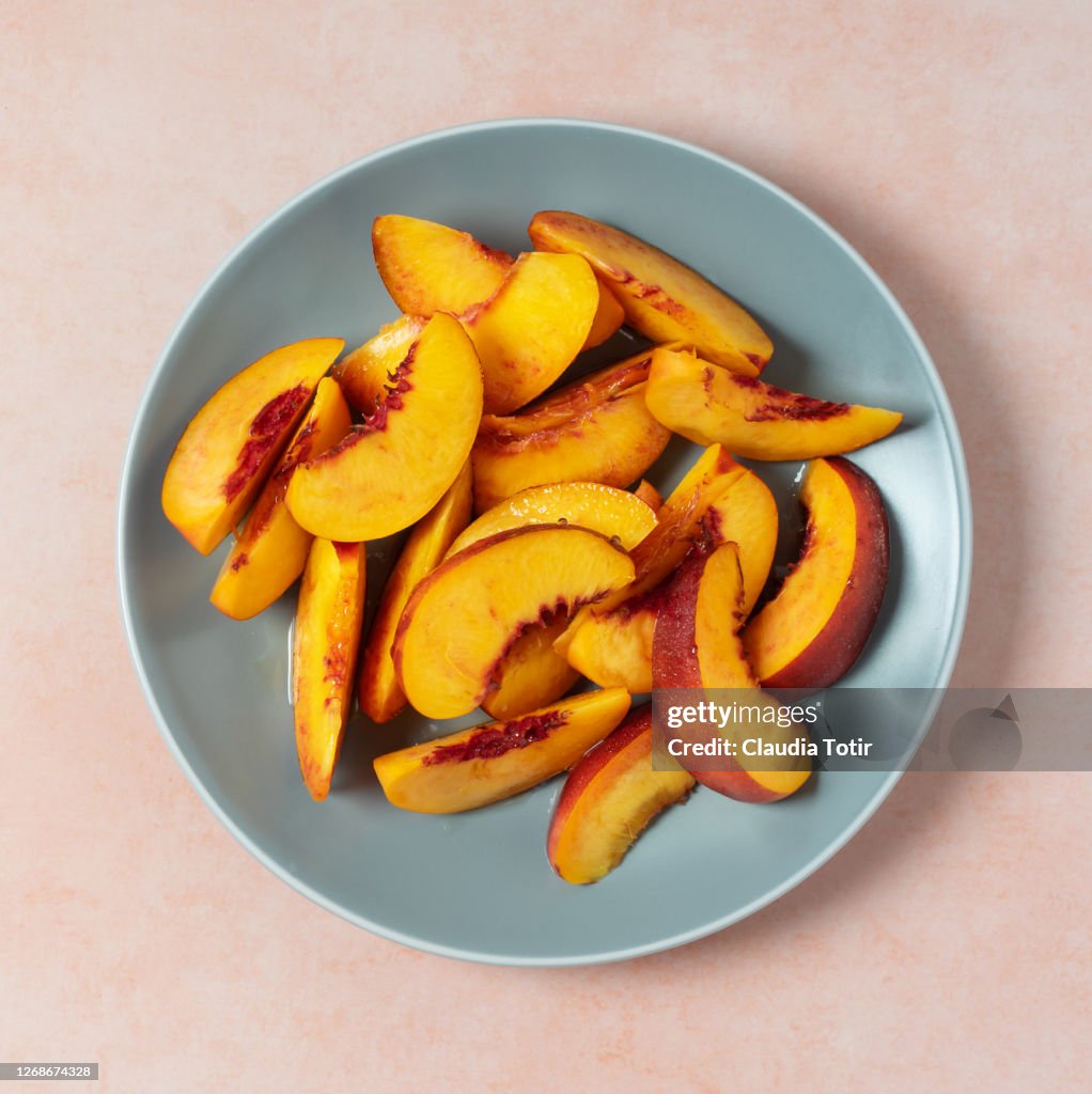 Slices of peach on a plate on light orange background