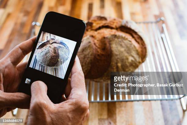 a man taking and sharing the photo of an homemade sourdough bread with mobile / smart phone - baking bread imagens e fotografias de stock