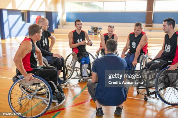 coach meeting with wheelchair basketball team in gymnasium - wheelchair basketball team stock pictures, royalty-free photos & images