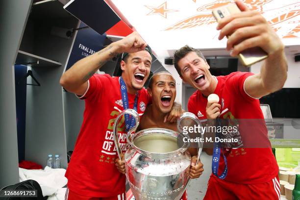 Philippe Coutinho, Thiago and Robert Lewandowski of FC Bayern Muenchen pose with the trophy in the dressing room following their team's victory in...