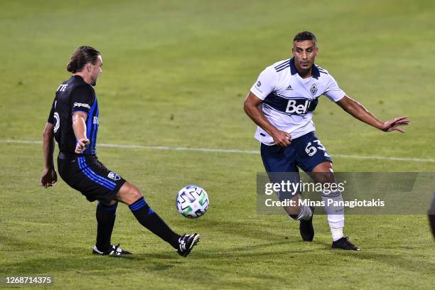 Samuel Piette of the Montreal Impact plays the ball near Ali Adnan of the Vancouver Whitecaps during the second half of the MLS game at Saputo...