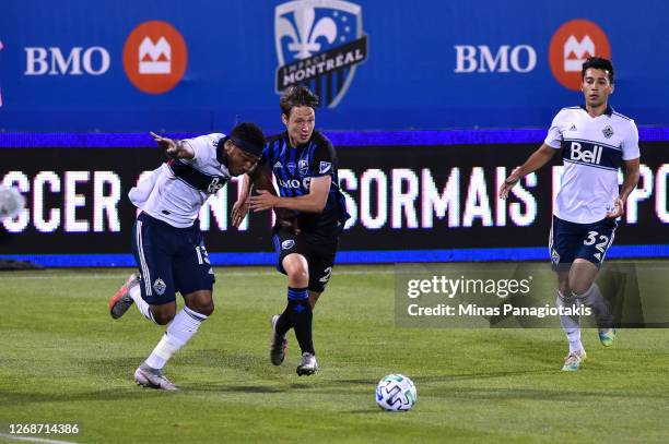 Lassi Lappalainen of the Montreal Impact runs for the ball against Derek Cornelius and Patrick Metcalfe of the Vancouver Whitecaps during the first...