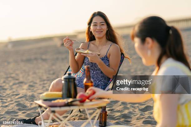 gruppe von freunden, die am strand grillen und das gespräch miteinander genießen - barbeque party woman stock-fotos und bilder