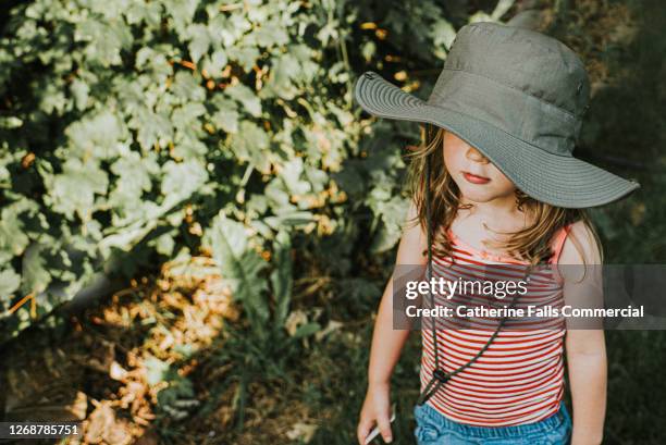 cute little girl outside in the sun wearing a wide brim hat - wide brim stock-fotos und bilder